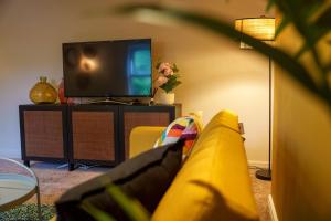 a living room with a yellow couch and a tv at Stay with airhgt @ Luxe Apartment in Central Harrogate in Harrogate