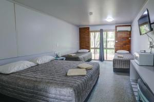 een hotelkamer met een bed en een televisie bij Tambo Mill Motel & Caravan Park in Tambo