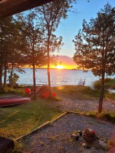 eine Feuerstelle am Ufer eines Sees bei Sonnenuntergang in der Unterkunft The Cove in Little Current