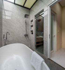 a bathroom with a tub and a shower and a sink at Verdant Bali Sekar Sari in Denpasar