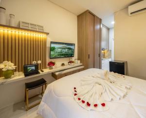 a bedroom with a large white bed and a television at Verdant Bali Sekar Sari in Denpasar
