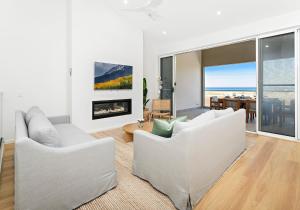 a living room with two white couches and a fireplace at Southcape, Gerroa in Gerroa