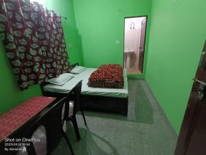 Grünes Zimmer mit einem Bett und einem Spiegel in der Unterkunft Abhishek Hotel , Sonprayag in Trijugi Nārāyan
