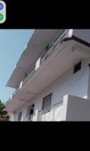 ein großes weißes Gebäude mit Fenstern und einem Balkon in der Unterkunft Abhishek Hotel , Sonprayag in Trijugi Nārāyan