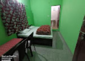 Grünes Zimmer mit einem Bett und einem Spiegel in der Unterkunft Abhishek Hotel , Sonprayag in Trijugi Nārāyan