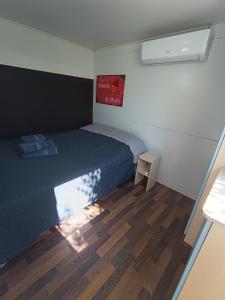 a small bedroom with a bed and a wooden floor at Hillbilly cabin, 2 studios in nature with terrace and parking in Skiathos