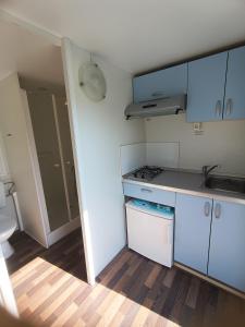 a small kitchen with blue cabinets and a toilet at Hillbilly cabin, 2 studios in nature with terrace and parking in Skiathos