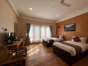 a hotel room with two beds and a desk at Paro Eco Lodge in Paro