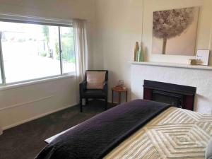 ein Schlafzimmer mit einem Kamin, einem Bett und einem Stuhl in der Unterkunft Marjalis Cottage, your perfect country getaway! in Wonthaggi