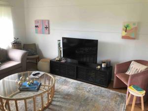 ein Wohnzimmer mit einem Flachbild-TV und einem Couchtisch in der Unterkunft Marjalis Cottage, your perfect country getaway! in Wonthaggi