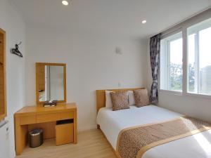 a bedroom with a bed and a desk and a mirror at Star House in Jeju
