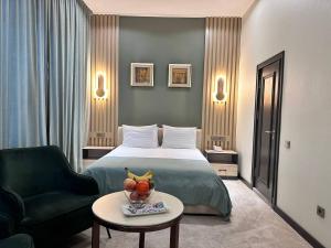 um quarto de hotel com uma cama, uma cadeira e uma mesa em HUSMA Hotel & Spa em Tashkent