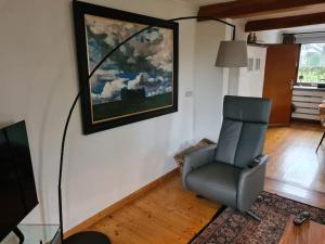 una sala de estar con una silla y una pintura en la pared en Haus Päsch nahe See mit beheiztem Whirlpool/Sauna, en Bütgenbach