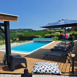 uma piscina com cadeiras e um guarda-sol em Le Domaine Vesque em Saint-Pierre-de-Clairac