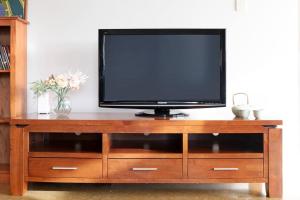 a television sitting on top of a wooden entertainment center at Artistic City Escape with Balcony and Parking in Darwin