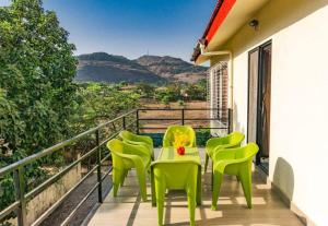 a table and chairs on a balcony with a view at THE PERFECT STAYS: MOUNTAIN MANOR VILLA in Lonavala