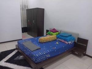 een slaapkamer met een bed met blauwe lakens en kussens bij MELUR HOMESTAY in Jitra