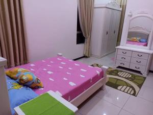 een slaapkamer met een roze bed en een spiegel bij MELUR HOMESTAY in Jitra