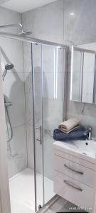 baño blanco con ducha y lavamanos en London gateway studio flat, en Borehamwood