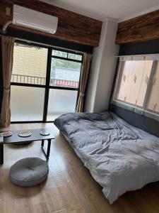 1 dormitorio con cama, mesa y ventanas en North River 302 Dandelion 新スタジアムの近く en Kami-nagarekawachō