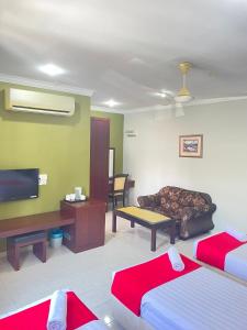 a room with two beds and a tv and a couch at Bayu View Hotel Klang in Klang