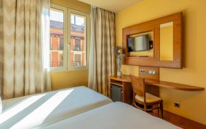 ein Hotelzimmer mit einem Bett, einem Schreibtisch und einem TV in der Unterkunft Sterling in Madrid