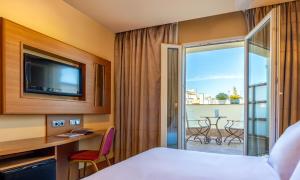 マドリードにあるスターリングのベッド、テレビ、バルコニーが備わるホテルルームです。