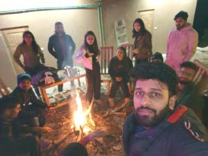 a group of people standing around a fire at Pyare Cafe Cottages And Tents in Gushaini