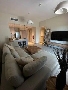 2 bedroom apartment Wabi Sabi in Yas في أبوظبي: غرفة معيشة مع أريكة كبيرة وتلفزيون