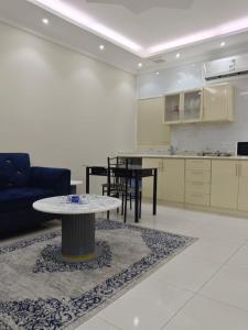 a living room with a table and a kitchen at فندق منازل الضيف in Al Madinah