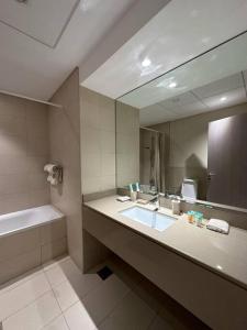 2 bedroom apartment Wabi Sabi in Yas في أبوظبي: حمام مع حوض ومرآة كبيرة