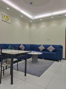 a living room with a blue couch and tables at فندق منازل الضيف in Al Madinah