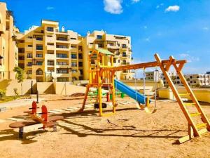 un parque infantil en la arena frente a un edificio en Al dau heights, en Hurghada