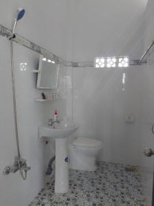 a white bathroom with a toilet and a sink at Đức Phát Homestay in Tân Phú