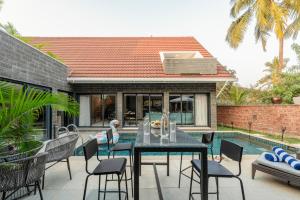 un patio con mesa y sillas junto a una piscina en City chic Luxury villa with Private pool available as 3bhk and 6Bhk en Old Goa