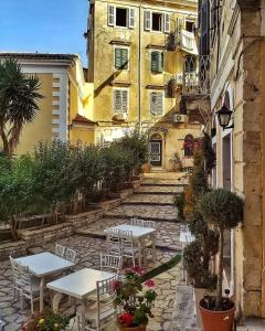 eine Terrasse mit Tischen und Stühlen vor einem Gebäude in der Unterkunft ''Dei Vecchi'' apartment in Kerkyra in Korfu-Stadt