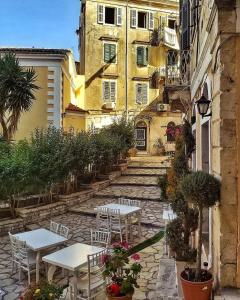 un patio con tavoli e sedie di fronte a un edificio di ''Dei Vecchi'' apartment in Kerkyra a Città di Corfù