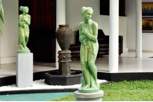 a green statue of a woman standing next to a vase at Thushine Hotel in Seeduwa