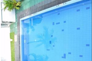 una piscina de azulejos azules con una palmera. en Thushine Hotel en Seeduwa