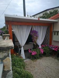 uma pérgola com cortinas e flores num quintal em Apartmani Betina - Petra Preradovića 2K em Betina