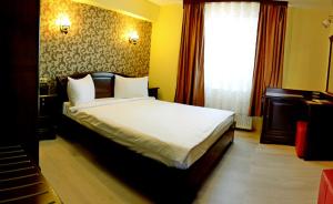 um quarto com uma cama grande com lençóis brancos e uma janela em Pensiunea Junior em Cluj-Napoca