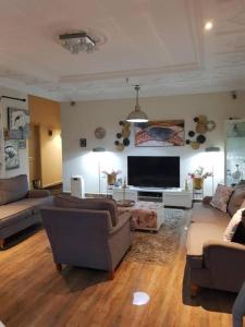uma sala de estar com sofás e uma televisão de ecrã plano em Nana Adu Guest House em Koforidua