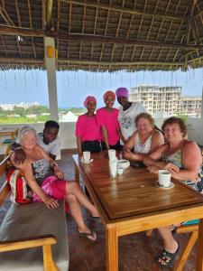 a group of people sitting around a wooden table at Cappadocia Hotel & restaurant in Nungwi