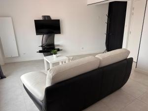 a living room with a black and white couch and a tv at Envies D’Ailleurs Centre Ville in Saint-Brevin-les-Pins