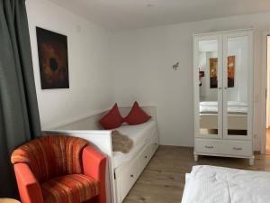1 dormitorio con cama, silla y espejo en Ferienwohung Auszeit am Eifelsteig, en Gemünden