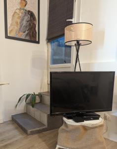 telewizor z płaskim ekranem siedzący na stole obok lampy w obiekcie La Suite Angoulême w mieście Angoulême