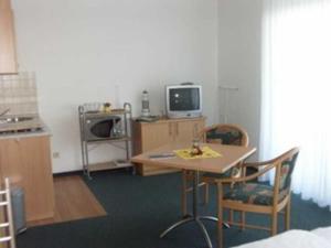 a room with a table and chairs and a tv at Appartementhaus Anne in Binz