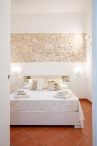 - un lit blanc avec des draps et des oreillers blancs dans l'établissement Casa ORCHIDEA D'ORO, à Syracuse