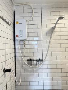 a white tiled bathroom with a shower head at Chubby 9 single room in Bangkok