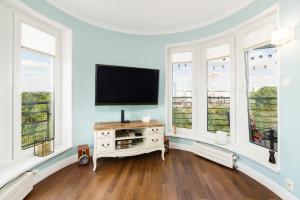 a living room with a flat screen tv and windows at Malta Lake Apartment Balcony and Parking by Renters Prestige in Poznań